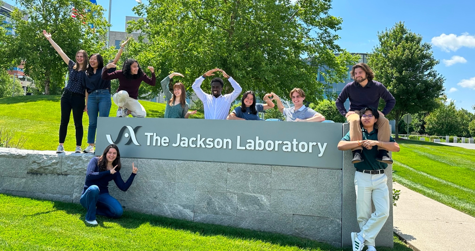 A group of students surrounding a wall with The Jackson Laboratory logo