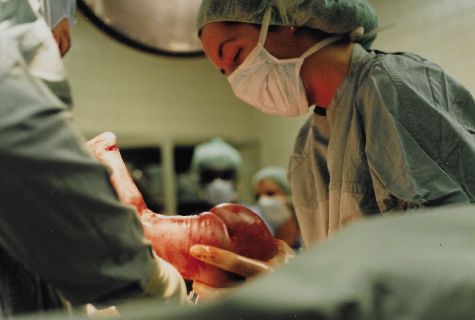 Dr. Susan Collins Black holding a newborn baby in an operating theater
